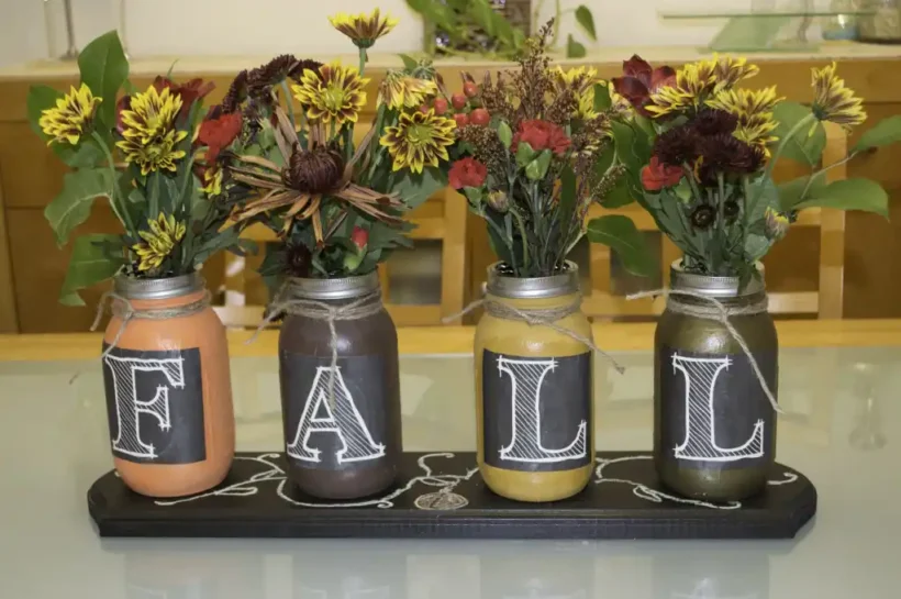Fall painted mason jar vases with autumn cut flowers.