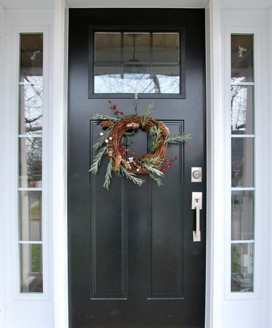 A simple and rustic holiday wreath on a black front door.