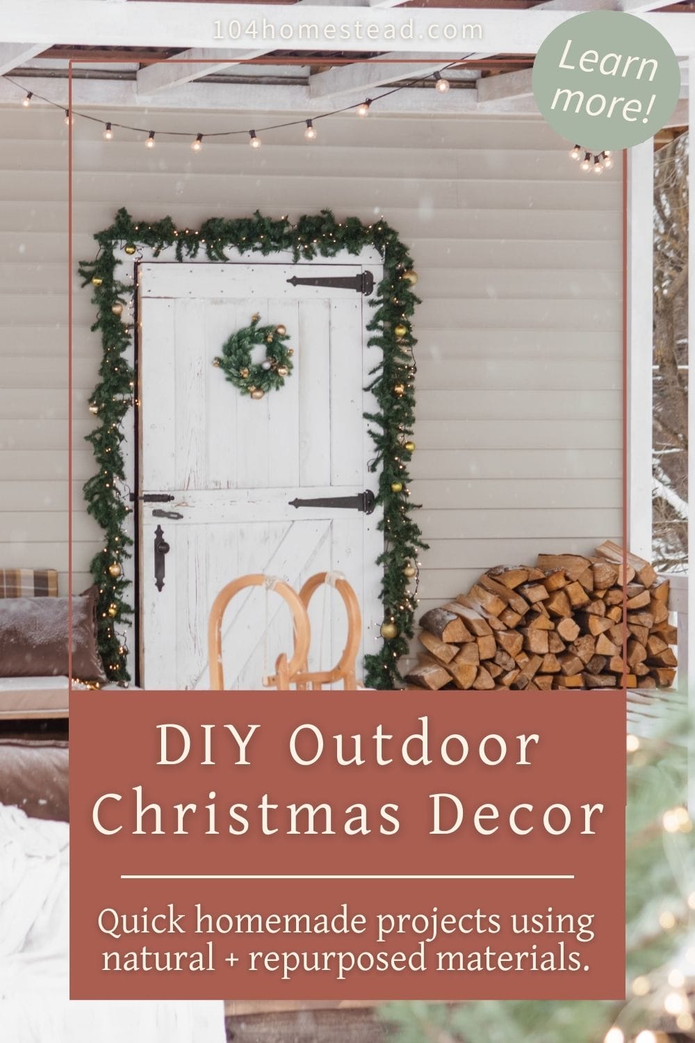 Outdoor Christmas porch decorated with evergreen garland around a white barn-style door, a small wreath, stacked firewood, and a wooden sled for a simple rustic holiday look.
