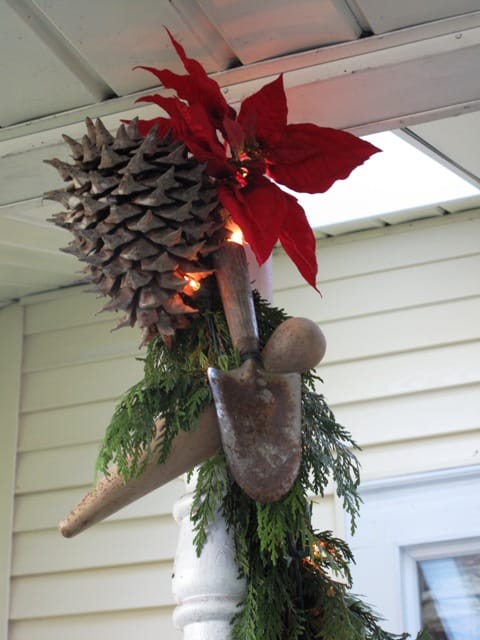 A cedar garland wraps around the porch columns and each is topped with a huge pinecone and more vintage tools.
