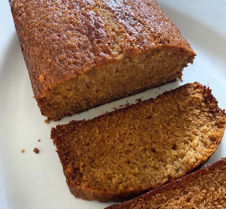 A simple honey cake loaf, sliced on a white plate.
