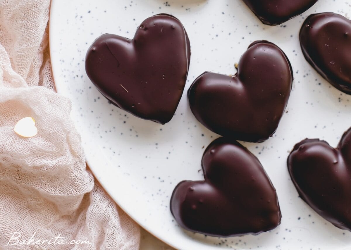 Chocolate peanut butter hearts on a speckled plate with paper hearts around it.