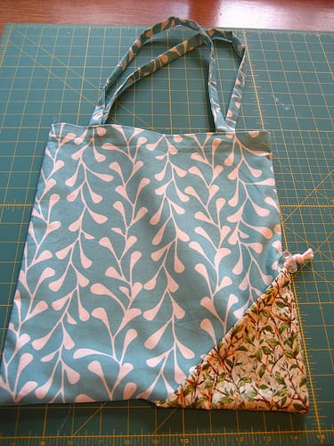 A teal leaf patterned foldable reusable bag.
