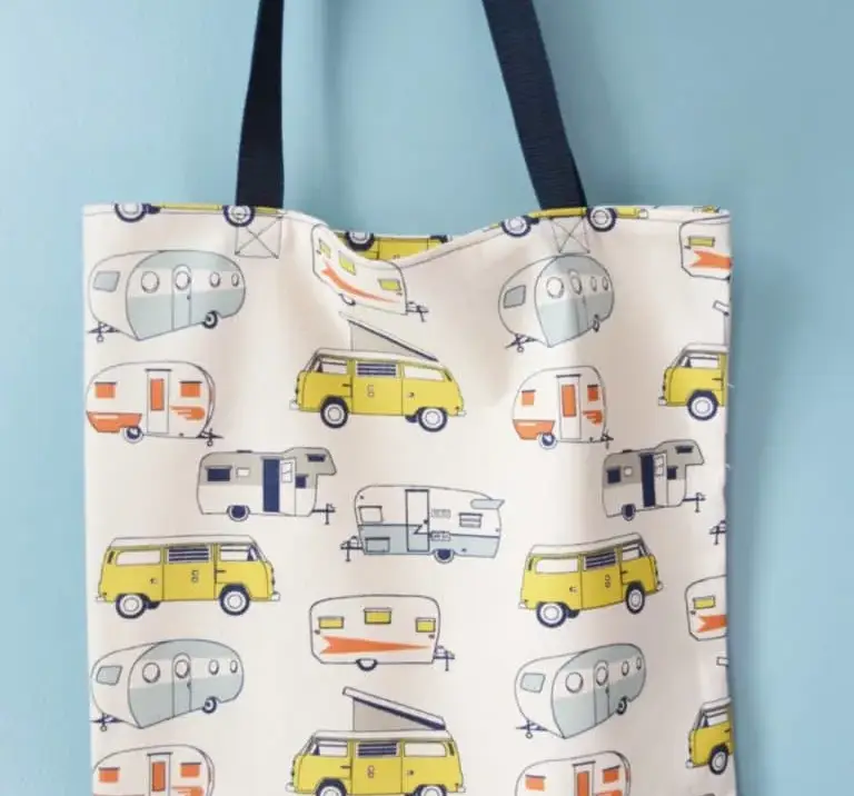 A cute canvas tote bag with old fashioned campers and a navy blue handle.