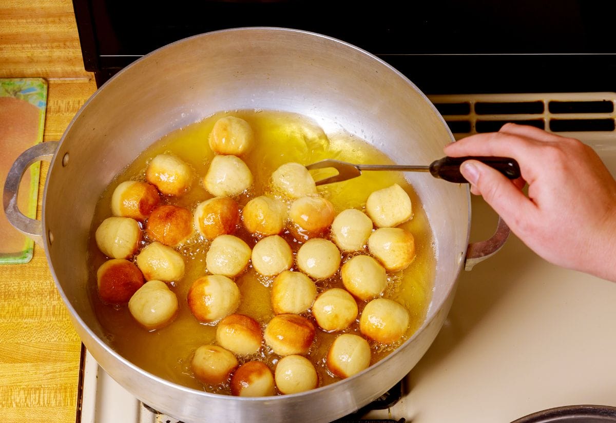 Frying donut holes in a large stockpot on the stove top.
