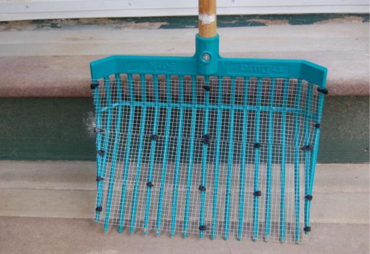 A stall rake with hardware cloth zip tied to it to make a large sifter.