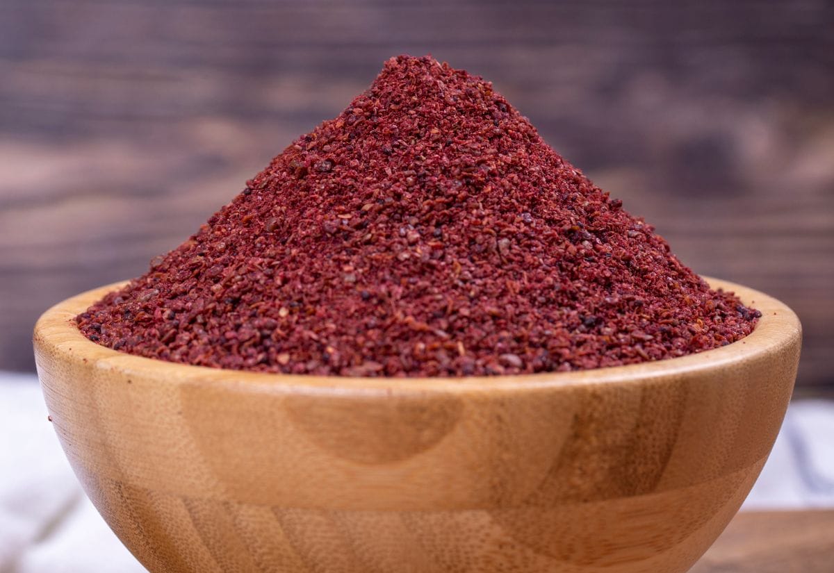 A bowl of ground staghorn sumac powder on a wooden surface. 