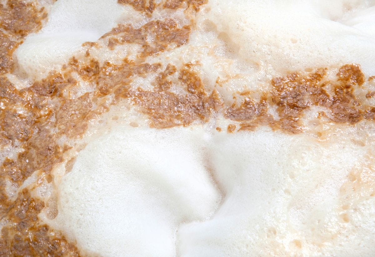 A close-up of foamy fermentation with yeast actively breaking down sugars in the beer.