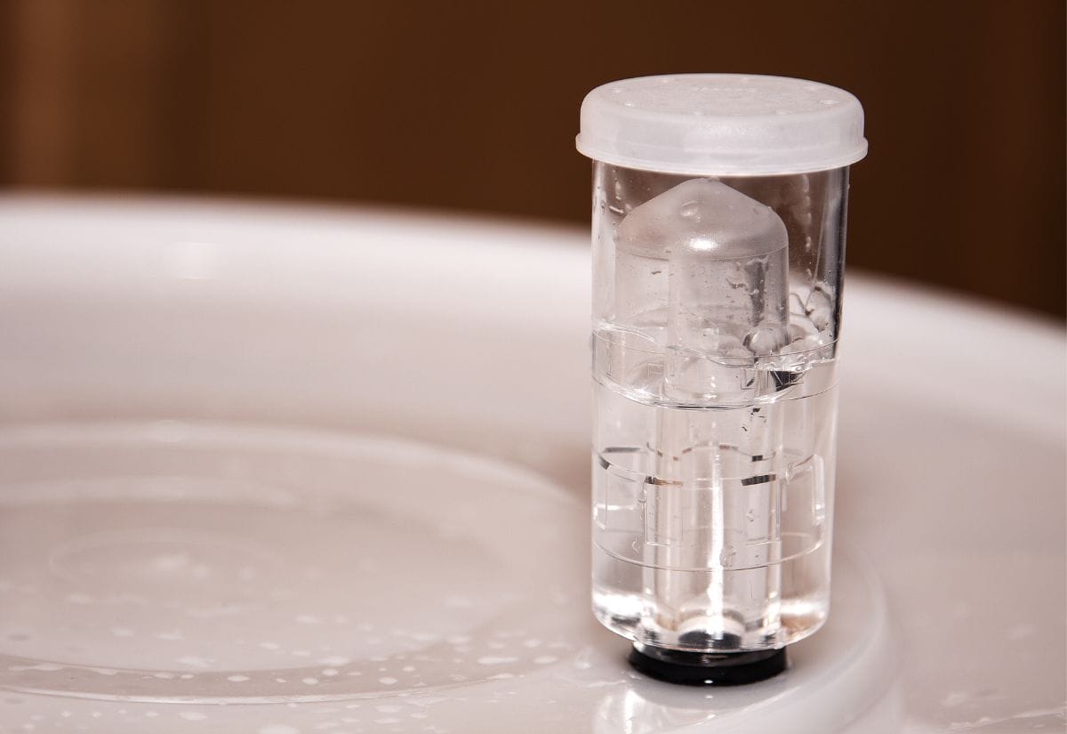 A plastic airlock filled with water attached to a fermenter, bubbling as fermentation takes place.