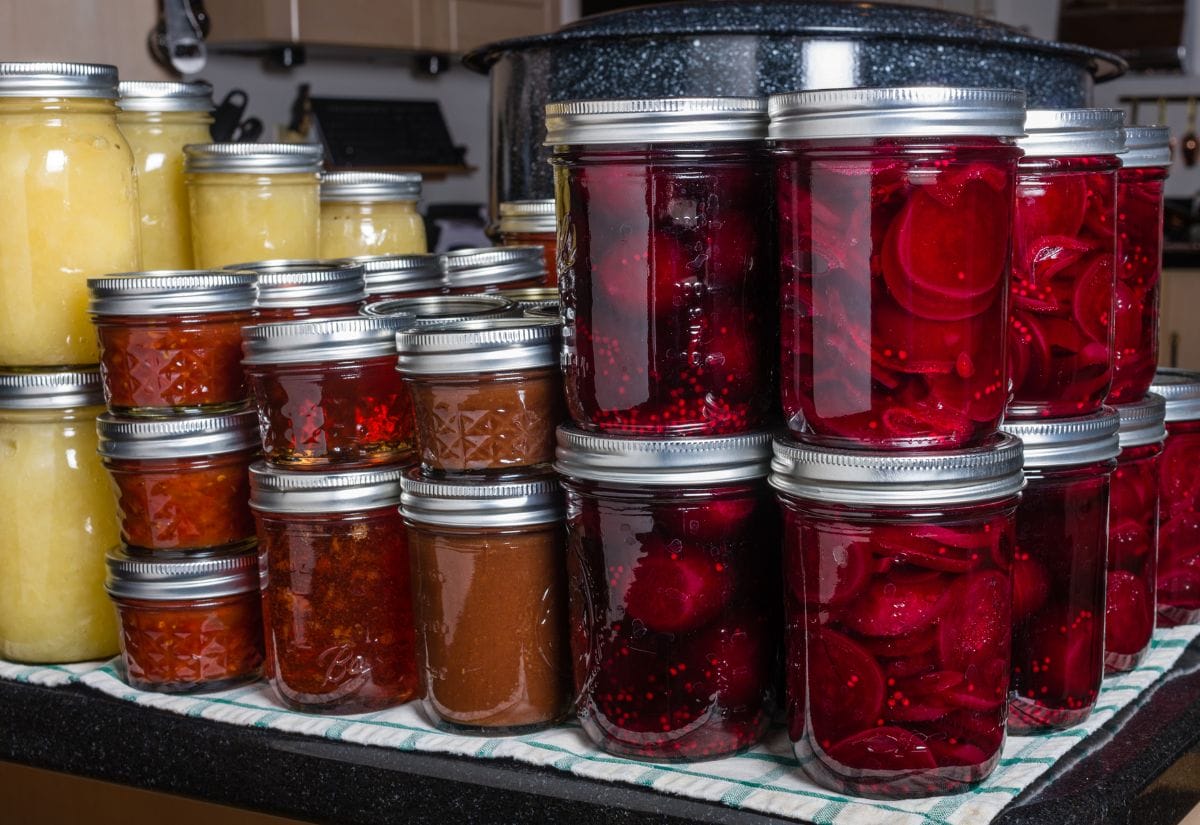 Jars of home-canned fruits and vegetables, neatly stacked on a kitchen counter, showcasing food preservation for long-term storage.