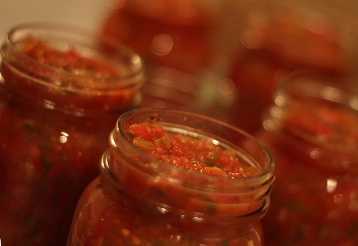 Close-up of freshly made salsa in glass canning jars, filled to the top and ready for processing or storage.