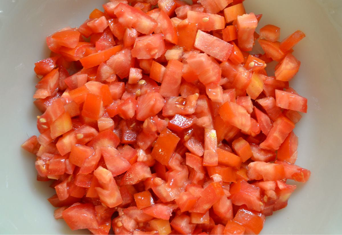 Close-up of freshly chopped ripe tomatoes in a white bowl, ready to be used as the base for homemade salsa.