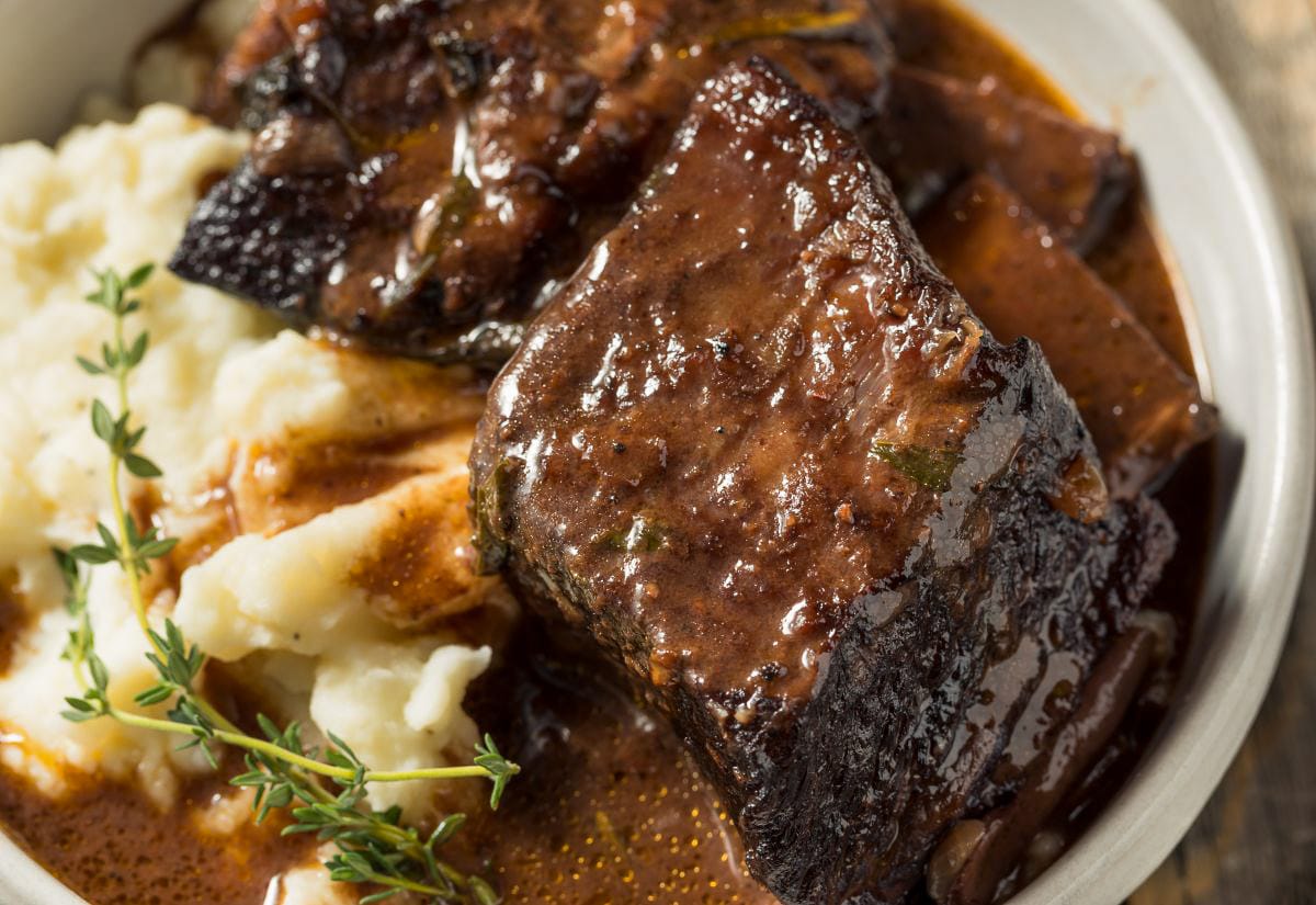 Tender braised beef short rib served over mashed potatoes and smothered in glossy pan-dripping gravy.