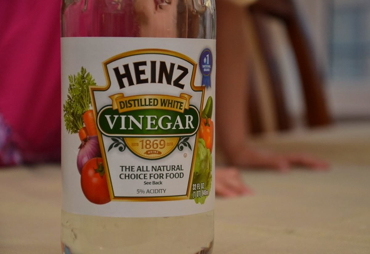 Bottle of distilled white vinegar standing on a kitchen counter, emphasizing a simple, multipurpose staple for natural cleaning.